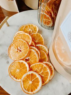 sliced oranges sitting on a marble plate next to a blender and glass jar