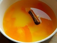 an orange liquid in a white bowl with a stick sticking out of it