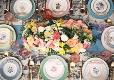 an overhead view of a table setting with plates, flowers and goldware on it