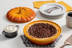 a pumpkin pie sitting on top of a white table next to a cup of coffee