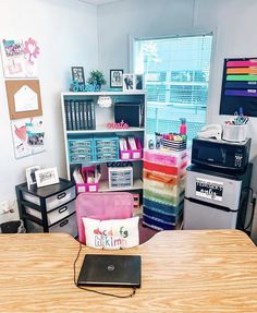 a room with desks, shelves and other office supplies on the table in front of a window