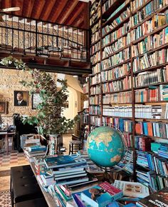 a room filled with lots of books and a globe on top of a table in front of a book shelf