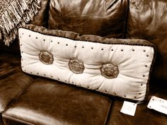 a brown leather couch with two pillows on it and a price tag attached to the pillow