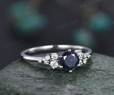 an engagement ring with a blue stone surrounded by white diamonds on top of a rock