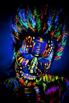 a person with neon makeup and hair in the dark