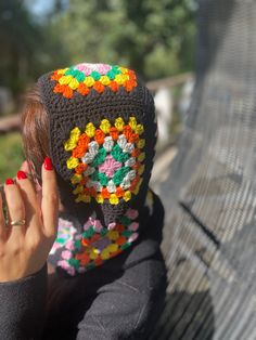 a woman wearing a crocheted granny hat covering her face