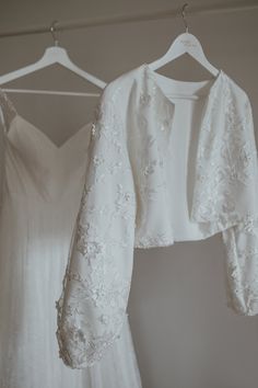 two white wedding dresses hanging on a rack