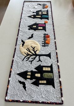 a long table runner decorated with black and white quilts, pumpkins and bats