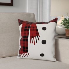 a snowman pillow sitting on top of a couch in front of a white chair