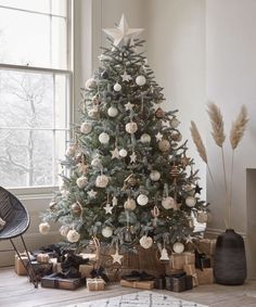 a decorated christmas tree in a living room with presents under it and an open window