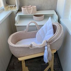 a wicker baby bassinet with white pillows and a tasselled pillow