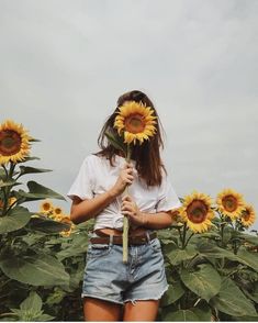 a woman standing in front of a field of sunflowers