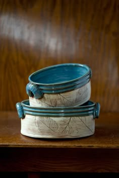 two blue and white bowls sitting on top of a wooden table next to each other