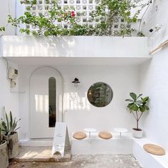 a white house with potted plants on the roof and an entry way leading to it