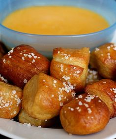 a white plate topped with croissants next to a bowl of orange soup