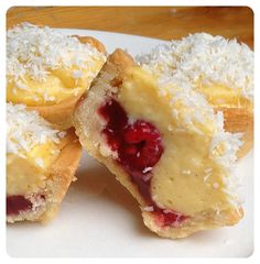 three pastries on a plate with coconut and raspberry toppings are cut in half