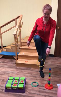 a woman kneeling down on the floor playing with blocks and toys in front of her