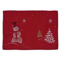 a red placemat with a snowman on it and trees in the back ground