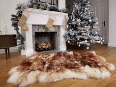 a living room with a christmas tree, fireplace and fake fur on the wooden floor