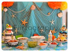 a table topped with lots of food next to a blue net covered wall behind it