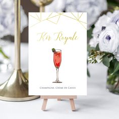 a card with a champagne creme on it sitting next to a vase filled with flowers