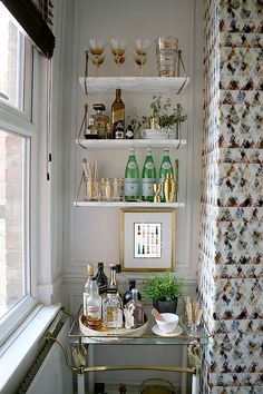 a bar cart in front of a window with bottles and glasses on top of it