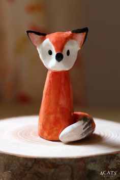 a small ceramic fox sitting on top of a tree stump