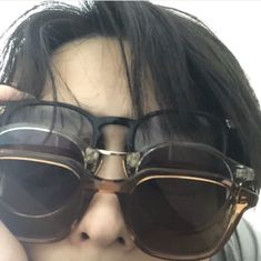 a close up of a person wearing sunglasses with one hand on their face and the other in front of them