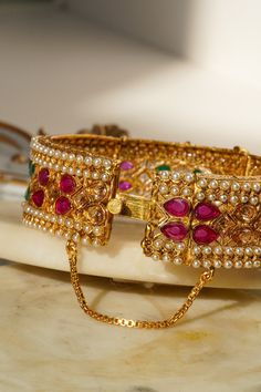 Introducing the Amika Bangle Set (Set of 2), a stunning addition to any jewelry collection. These gold-plated bangles feature intricate designs adorned with pearls and vibrant multicolor stones, including green and ruby accents. The detailed floral and petal patterns exude elegance and sophistication, making these bangles & bracelets set perfect for desi weddings and special occasions. The Amika Bangle Set showcases the timeless beauty of Navratan craftsmanship. The bangles are designed with an Navratan Bangles, Bangles And Bracelets, Bangles Set, The Bangles, Gold Plated Bangles, Bangle Bracelet Set, Bracelets Set, Bangles Bracelets, Desi Wedding