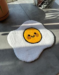 a smiley face rug on the ground next to a potted plant