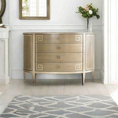 a white and gold dresser sitting in a room next to a mirror on the wall