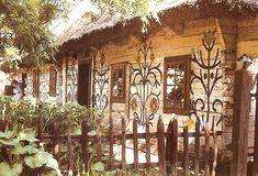 a small house with an iron fence around it's perimeter and windows on the side