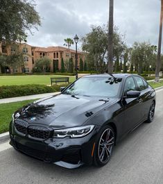 a black bmw is parked on the side of the road