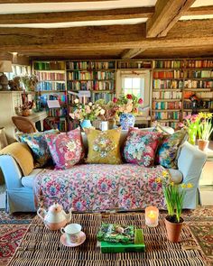 a living room filled with lots of furniture and bookshelves full of books on top of them