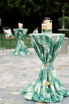 the table is covered with green palm leaves and has a candle on it for an elegant touch