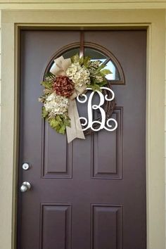 a front door with a wreath and monogrammed letters on the top, along with a bow