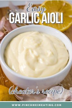 an easy garlic aioli recipe in a white bowl with lemons and garlic on the side