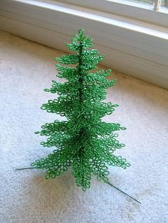 a green plastic christmas tree sitting on top of a white carpet next to a window