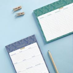 two notepads sitting on top of a desk next to a pen and pencil