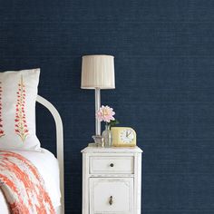 a bedroom with blue walls and a white night stand next to a lamp on a nightstand