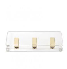 three gold - plated metal clips are attached to a clear acrylic holder