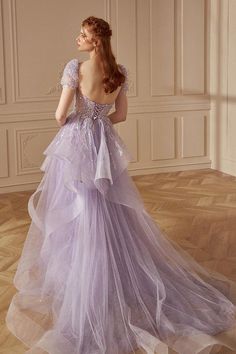 a woman in a purple dress standing on a wooden floor with her back turned to the camera