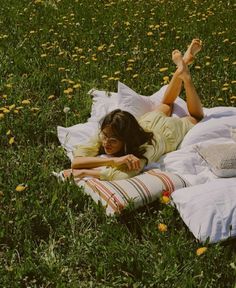 a woman laying on top of a blanket in the grass