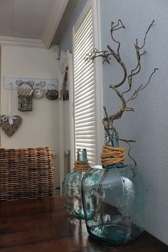 two vases sitting on top of a wooden table next to a basket and window