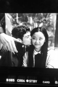 a man kissing a woman on the cheek in front of a tv screen with people watching