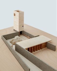 a model of a house made out of wood and concrete with a rock in the foreground