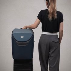 a woman standing next to a suitcase with the lid open and it's handle extended