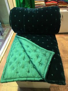 a green and black blanket sitting on top of a white bench in front of a store window