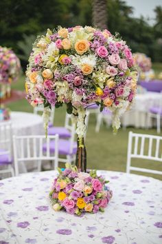 an arrangement of flowers is on top of a table at a wedding reception in the park