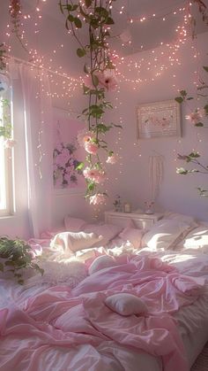 a bed with pink sheets and flowers hanging from the ceiling